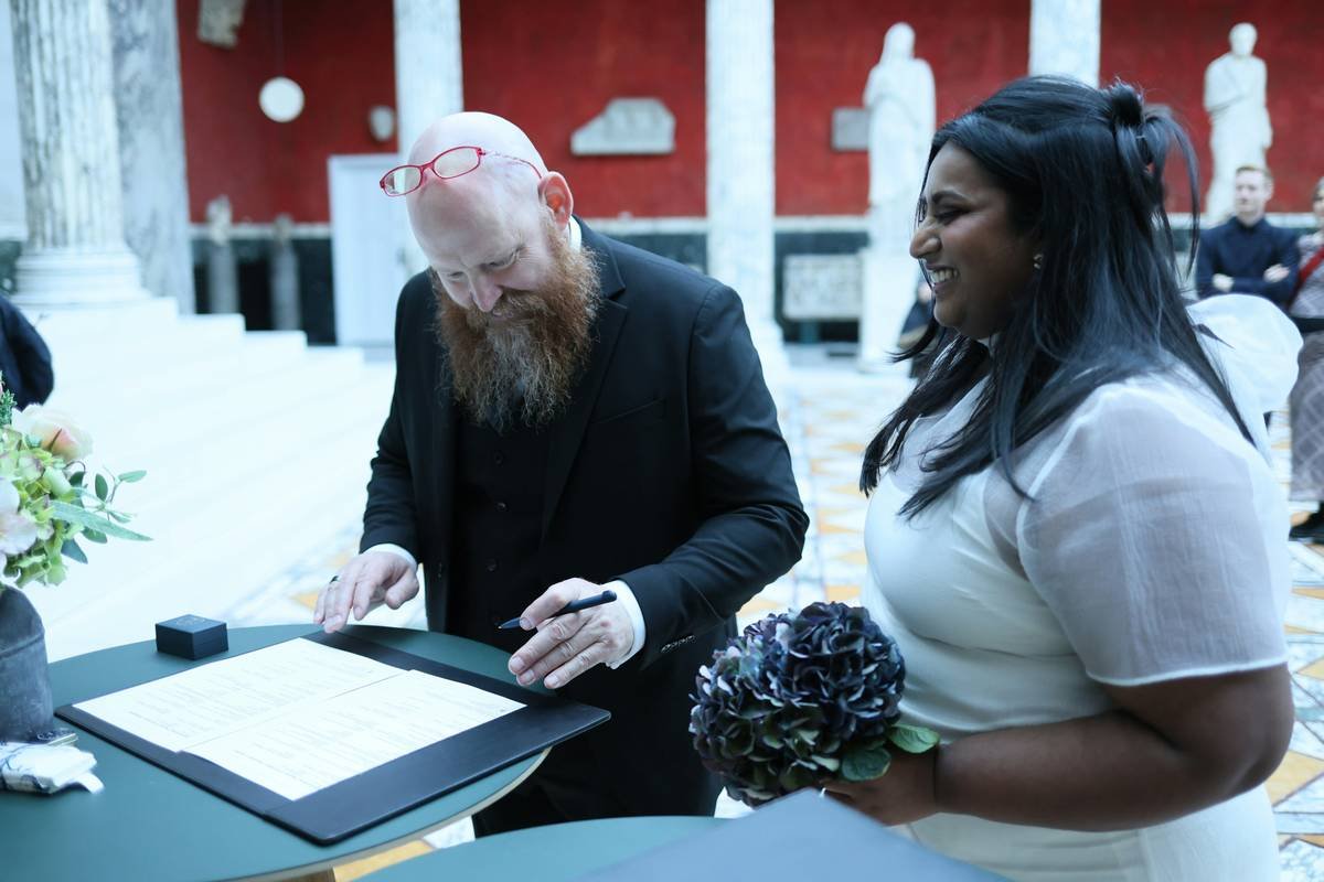 A couple signing marriage documents with a bouquet.